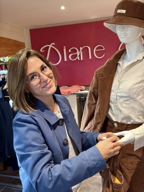 Femme en showroom Diane G, souriante, devant le logo